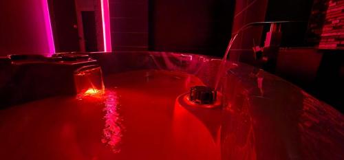 La salle de bains est pourvue d'une baignoire rouge et d'une lumière rouge. dans l'établissement L'Aphrodite Jacuzzi privatif, à Saint-Zacharie