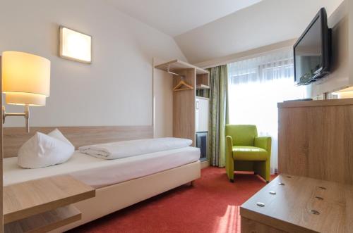 a hotel room with a bed and a tv and a chair at Garden Hotel in Nürnberg