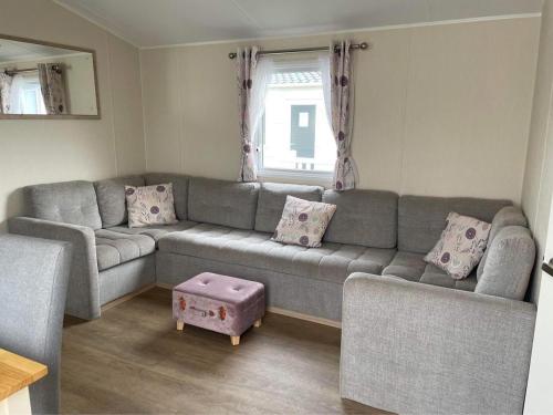 a living room with a gray couch and a window at Emma's Oasis 4-bedroom caravan at Durdle Door in West Lulworth