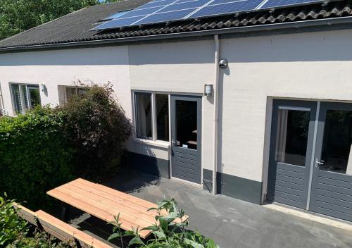 a house with solar panels on the roof and a bench at Waddenhoes Gastenverblijven in Pieterburen