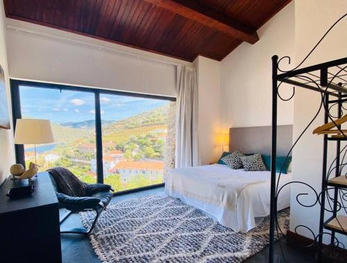 ein Schlafzimmer mit einem Bett und einem großen Fenster in der Unterkunft casa das ameias in Folgosa