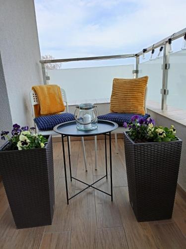 a table and two potted plants on a balcony at Apartament z garażem blisko dwóch jezior na Warmii i Mazurach in Biskupiec
