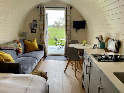 uma cozinha e sala de estar com um sofá e uma mesa em Abbey farm luxury glamping em Rhuddlan