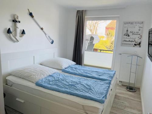 Schlafzimmer mit einem Bett mit blauer Bettwäsche und einem Fenster in der Unterkunft Baltic Nr. 3 in Scharbeutz