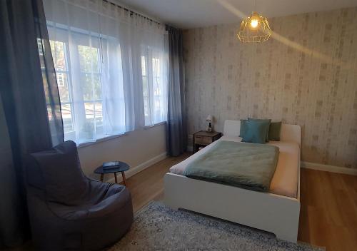 1 dormitorio con 1 cama, 1 silla y 1 ventana en Elegante Einzimmerwohnung, en Flensburg