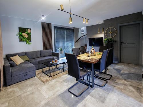 uma sala de estar com um sofá, uma mesa e cadeiras em TRZY SOSNY LOFT APARTMENTS em Ściegny