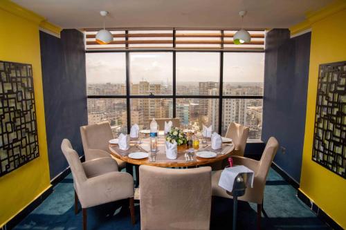 een eetkamer met een tafel en stoelen en een groot raam bij Golden Tulip Dar Es Salaam City Center Hotel in Dar es Salaam