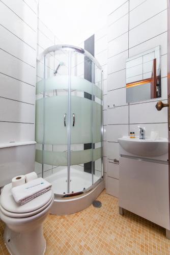 a bathroom with a shower and a toilet and a sink at Local da Trindade Guesthouse in Lagos