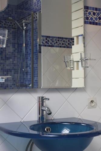 La salle de bains est pourvue d'un lavabo bleu et d'un miroir. dans l'établissement la suite Au bon Marechal, à Giverny