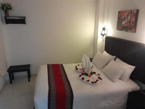 a bedroom with a bed with two plates of flowers on it at Margarita's House Machupicchu in Machu Picchu