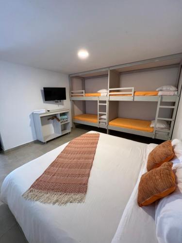 a bedroom with a bed and bunk beds with a television at La posada de Rubi in Salento