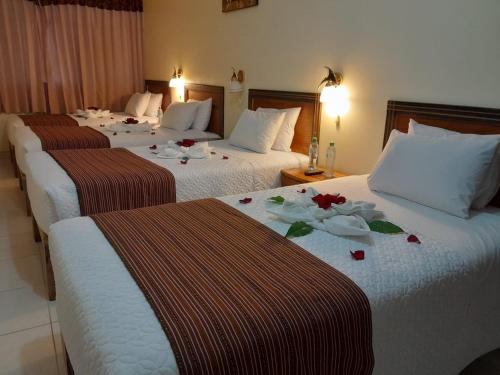 Tres camas en una habitación de hotel con flores. en Margarita's House Machupicchu, en Machu Picchu