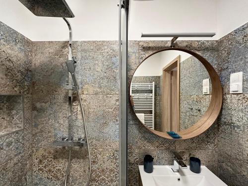 ein Bad mit einer Dusche, einem Waschbecken und einem Spiegel in der Unterkunft Sunshine Resort Blue Apartman in Zamárdi