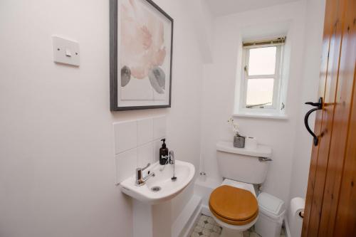 Baño blanco con aseo y lavamanos en Carters Cottage - Rudge Farm Cottages, en Bridport