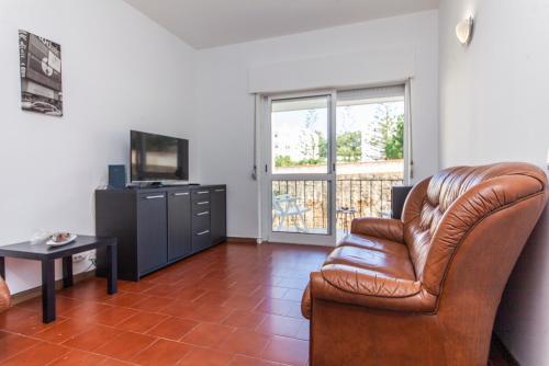 a living room with a leather chair and a television at Local da Trindade Guesthouse in Lagos
