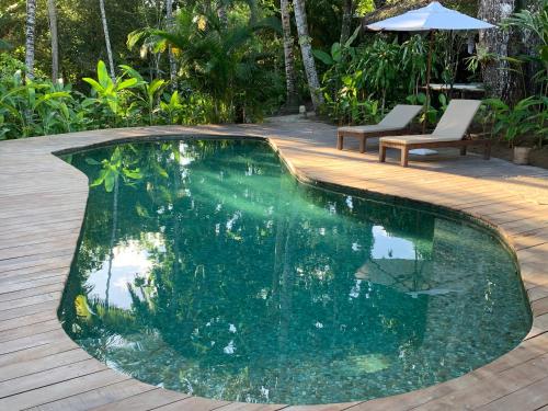 una piscina en un patio trasero con terraza de madera en Pousada Calypso, en Trancoso