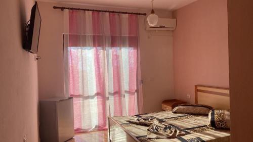 Habitación con cama y ventana con cortina en Hotel Odeon 3, en Vlorë