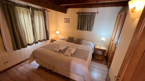 a bedroom with a bed with two towels on it at Hosteria y Cabañas Posada Quinen in San Martín de los Andes