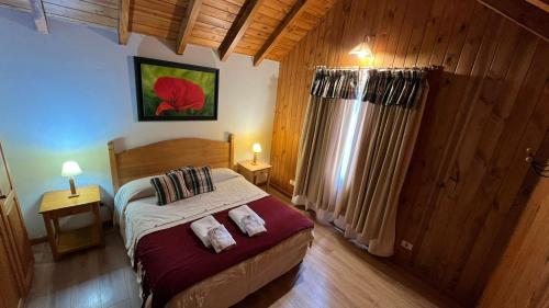 a bedroom with a bed and two pillows on it at Hosteria y Cabañas Posada Quinen by Nordic in San Martín de los Andes