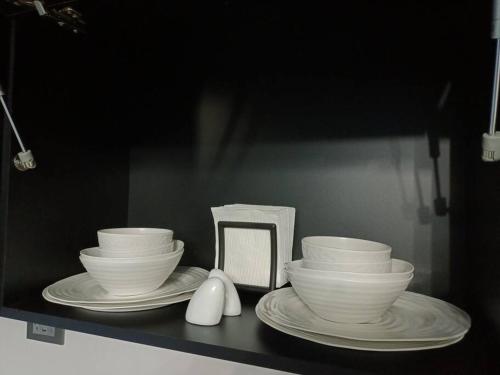 three bowls and plates on a shelf with a computer at moderno apartamento en el centro de la ciudad in Chihuahua