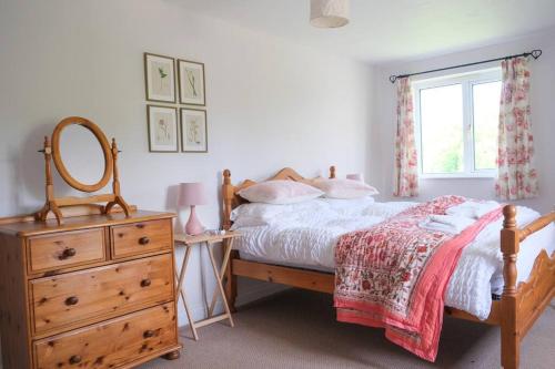 um quarto com uma cama, uma cómoda e uma janela em Spacious North Devon villa with beautiful garden em Bideford