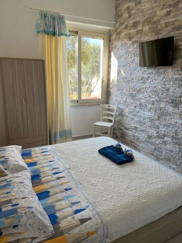 una camera con letto e TV su un muro di mattoni di B&B Isola Mia a La Maddalena
