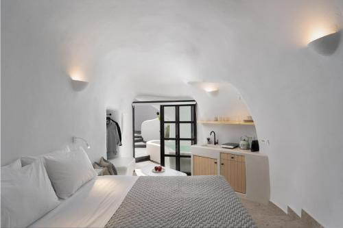 Habitación blanca con cama y espejo en Nisó Cave Suites en Megalokhori