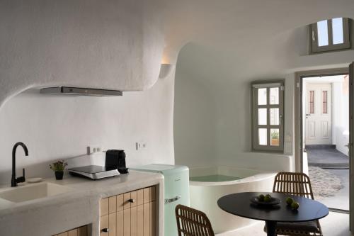 a kitchen with a sink and a table and a tub at Nisó Cave Suites in Megalokhori