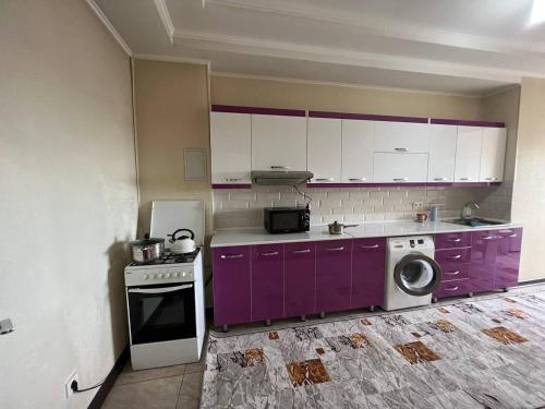eine Küche mit lila Schränken und einer Waschmaschine in der Unterkunft apartment on Turusbekova 13 in Bischkek