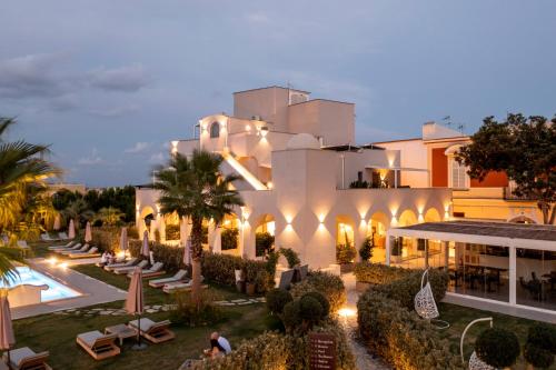 a large white building with a pool and palm trees at Insula Boutique Hotel in Procida