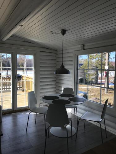 a dining room with a table and chairs and windows at Bastöstugby stuga 17 in Pålsböle