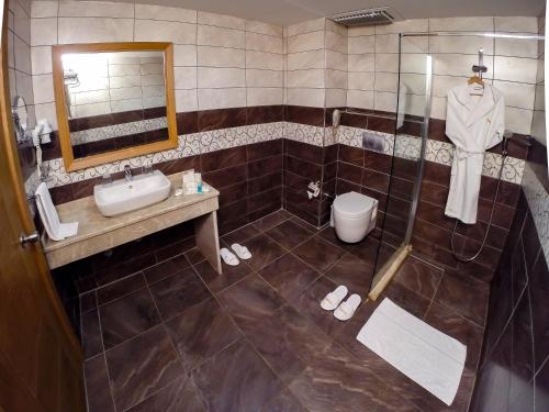 a bathroom with a sink and a toilet and a mirror at Club Hotel Belpınar in Beldibi
