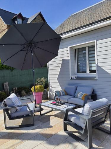 un patio con 2 sillas y una sombrilla en Véritable maison de vacances à 500 m des plages, en Saint-Malo
