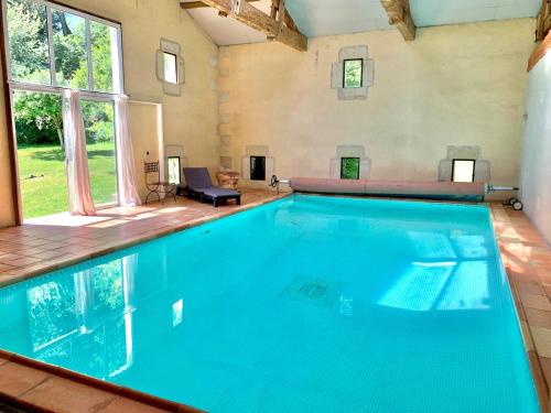 een groot zwembad in een kamer met een groot raam bij Château Le Baudou in Coutras