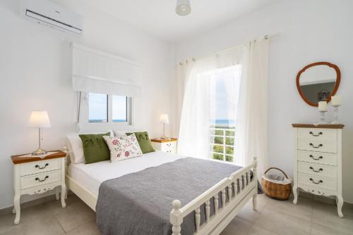 a white bedroom with a bed and a window at Endless Blue in Xerokampos
