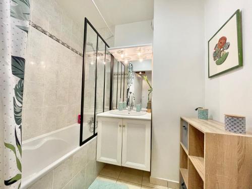 La salle de bains est pourvue d'une baignoire blanche et d'un lavabo. dans l'établissement LA LOUSIANE - Confort - Wifi - Parking privé - Terrasse - Centre Ville, à Quimper