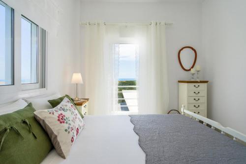 a white bedroom with a bed and a window at Endless Blue in Xerokampos