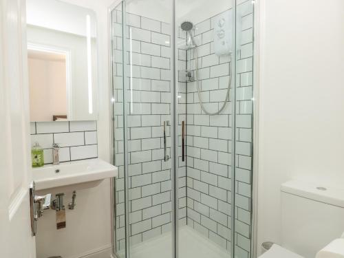 eine Glasdusche im Bad mit Waschbecken in der Unterkunft Grants Cottage in Dartmouth