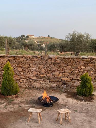 a fire pit in front of a stone wall at Monte da Parreira in Cabeça de Carneiro
