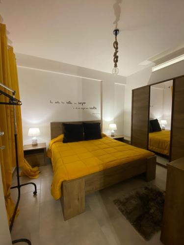 a bedroom with a yellow bed and a mirror at Cala Holidays vicino Aeroporto&Mare in Carini