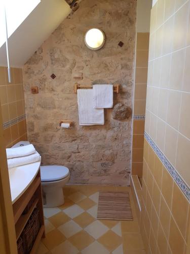 La salle de bains est pourvue de toilettes et d'un mur en pierre. dans l'établissement Le Moulin de Jules et Akasha, à Labastide-Murat