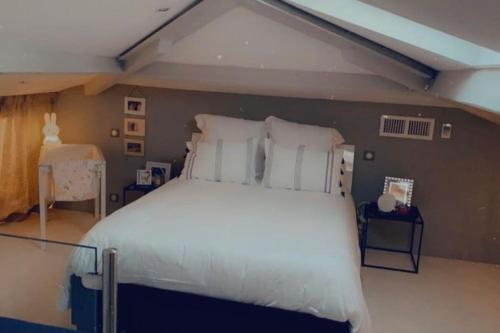 1 dormitorio con 1 cama grande con almohadas blancas en Appartement CANNES, vue mer triples exposition, en Cannes
