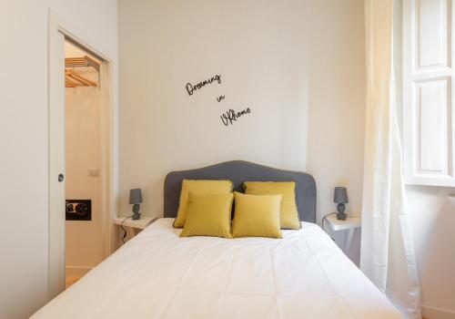 um quarto com uma cama branca com travesseiros amarelos em VRhome em Roma