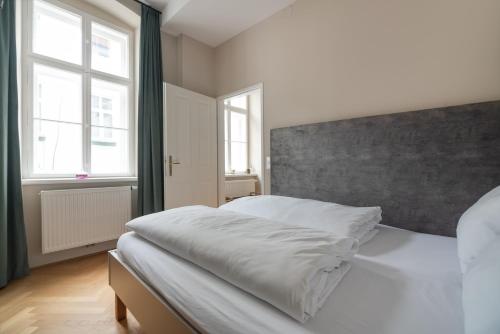 1 Schlafzimmer mit einem weißen Bett und 2 Fenstern in der Unterkunft Hochwertiges Apartment mit direkter Anbindung zum Zentrum in hippen Viertel in Wien