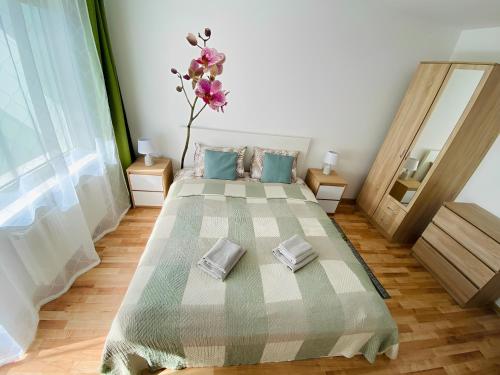 a bedroom with a bed and a vase with flowers on it at Coastal Comfort Apartments in Liepāja