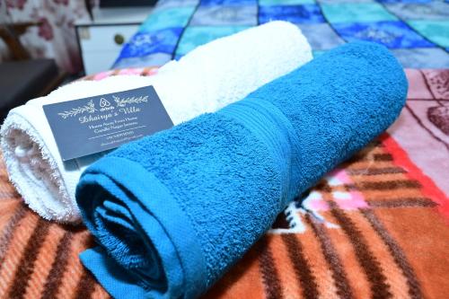 uma toalha enrolada azul e branca numa cama em Dhairya's Villa Home Away From Home em Jamu