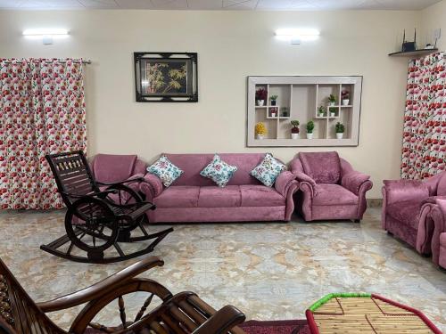 uma sala de estar com um sofá roxo e cadeiras em Dhairya's Villa Home Away From Home em Jamu