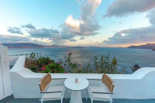 a patio with a table and chairs and a view of the ocean at Helianthus Dream Homes in Oia