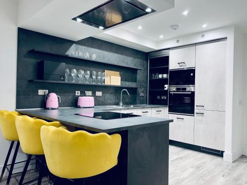 a kitchen with yellow bar stools and a pink appliance at Glasgow City Central Executive Triplex House, 3 Bedroom 3 Bathrooms 1 living room Kitchen - Huge Terrace for Master Bedroom - Private E Parking LEZ Congestion Zone Free - Garden - 5 mins drive to City Centre Central Station in Glasgow