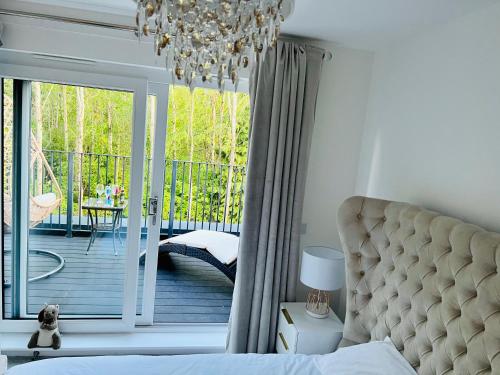 a bedroom with a bed and a balcony with a chandelier at SEC HYDRO Executive Triplex Townhouse, Glasgow City Central, 3 Bedrooms/3 Bathrooms, 1 Living room/kitchen, 3 Floors, Master Bed's TERRACE, Main door, Garden, (Gym/Sauna/Steam/Indoor Swimming Pool Access), Parking - By CALA Homes in Glasgow